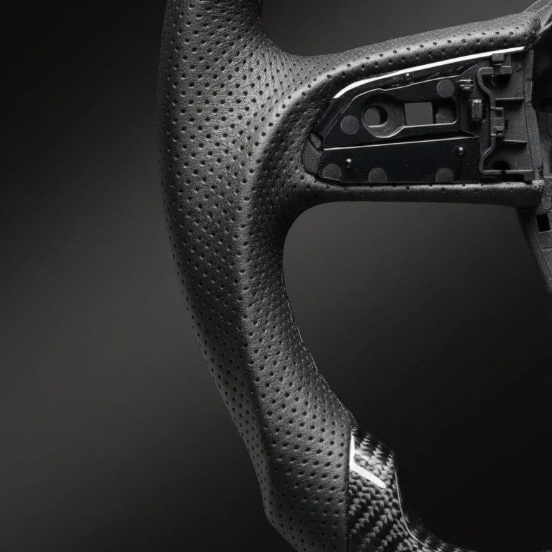 Close-up of a black steering wheel with visible stitching on a dark background